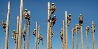 Arbeiter mit Kletterausrüstung besteigen gleichzeitig Pfähle